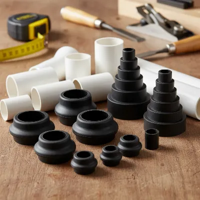 A collection of various adapters for connecting a shop vacuum to a table saw, including rubber reducers, PVC fittings, and flexible hoses arranged on a workbench with woodworking tools.